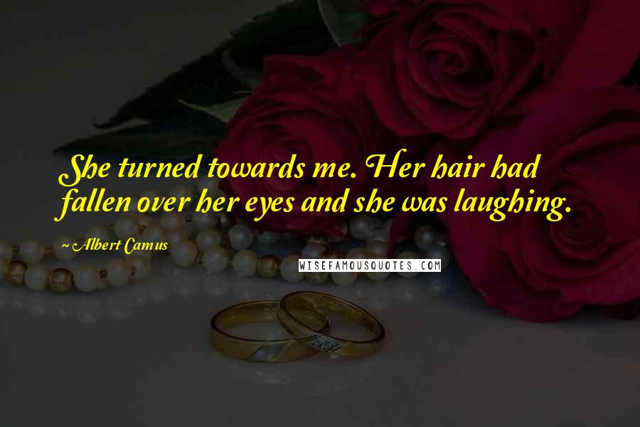 Albert Camus Quotes: She turned towards me. Her hair had fallen over her eyes and she was laughing.