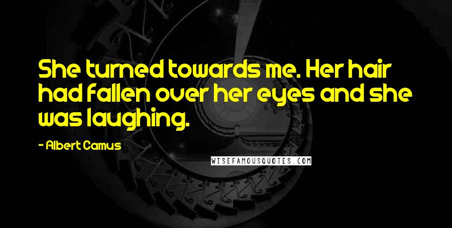 Albert Camus Quotes: She turned towards me. Her hair had fallen over her eyes and she was laughing.
