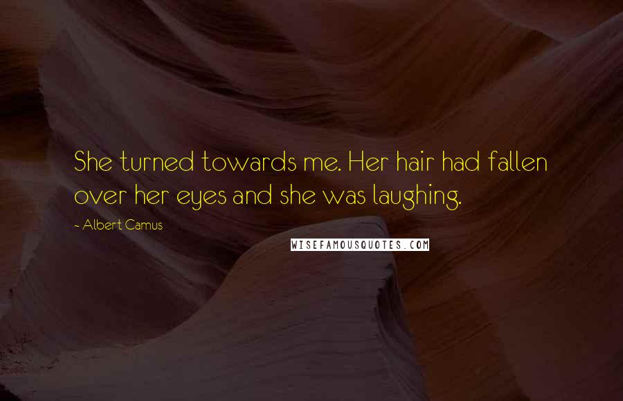 Albert Camus Quotes: She turned towards me. Her hair had fallen over her eyes and she was laughing.