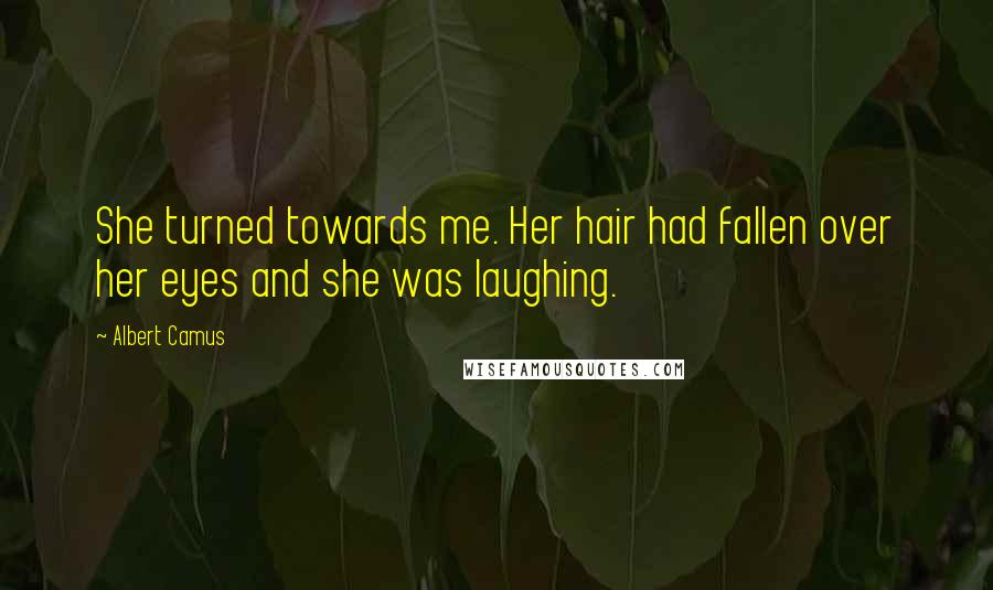 Albert Camus Quotes: She turned towards me. Her hair had fallen over her eyes and she was laughing.