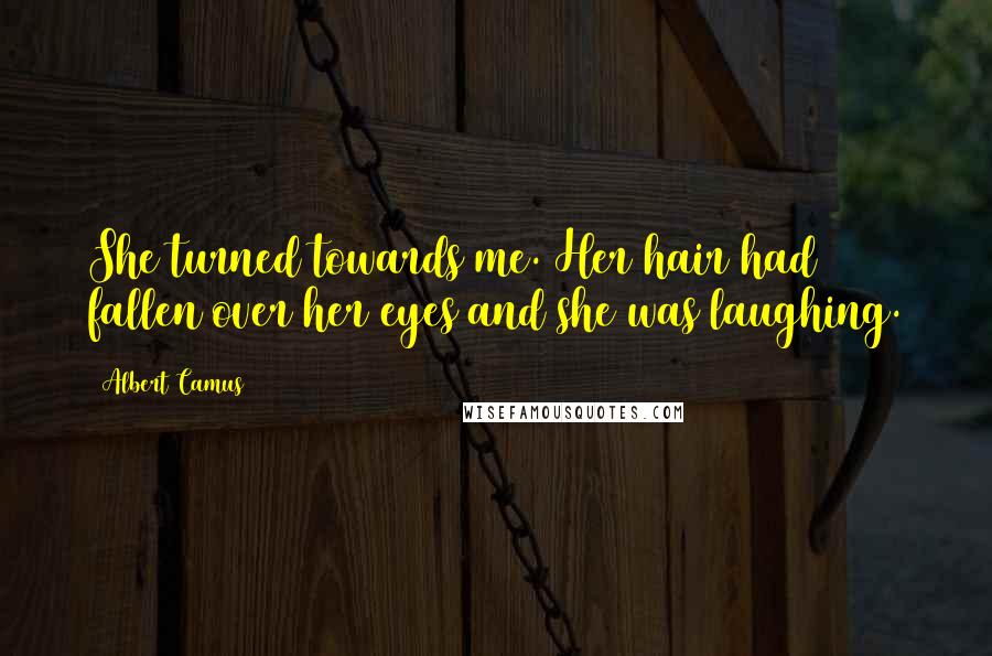 Albert Camus Quotes: She turned towards me. Her hair had fallen over her eyes and she was laughing.