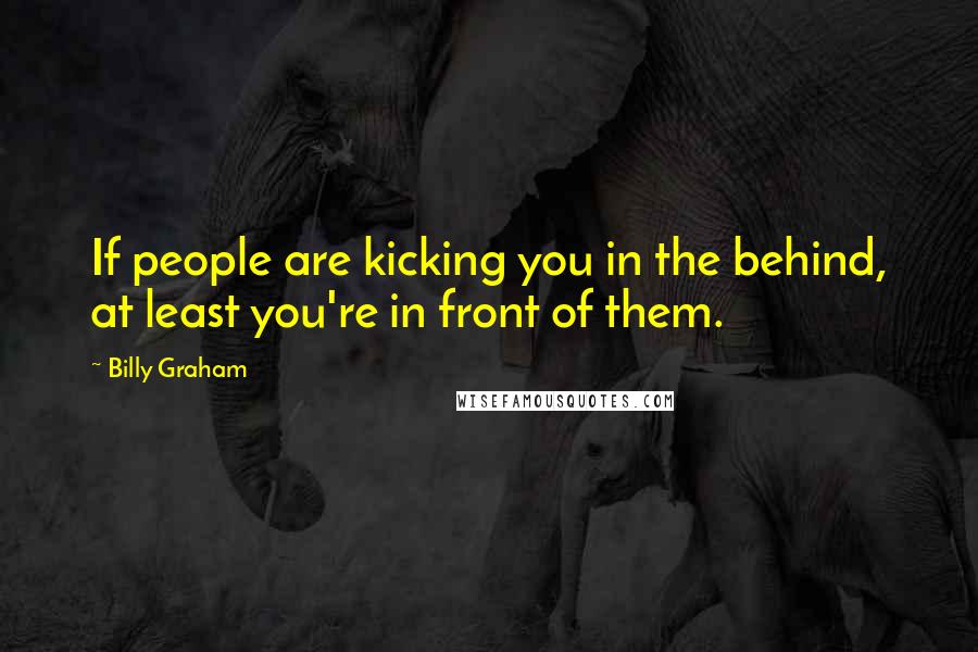 Billy Graham Quotes: If people are kicking you in the behind, at least you're in front of them.