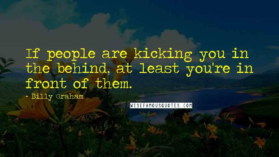 Billy Graham Quotes: If people are kicking you in the behind, at least you're in front of them.