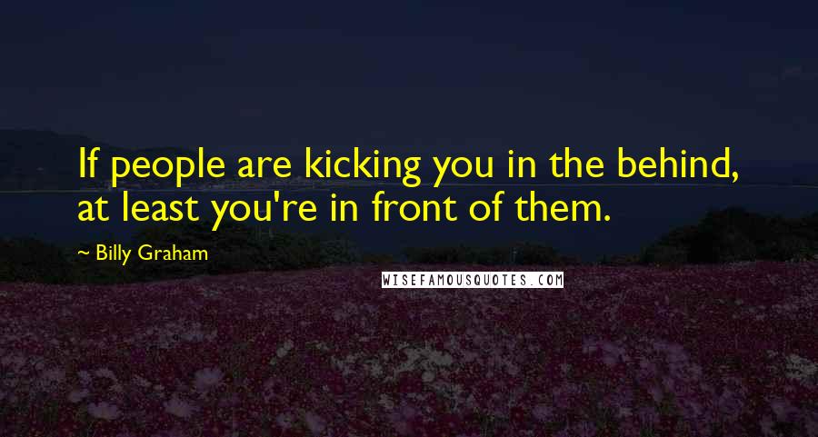 Billy Graham Quotes: If people are kicking you in the behind, at least you're in front of them.