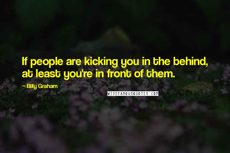 Billy Graham Quotes: If people are kicking you in the behind, at least you're in front of them.