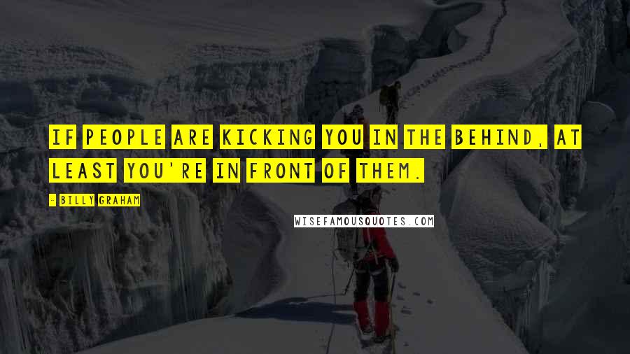 Billy Graham Quotes: If people are kicking you in the behind, at least you're in front of them.