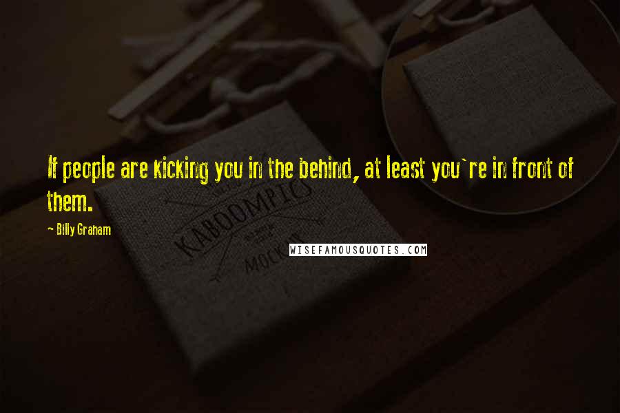 Billy Graham Quotes: If people are kicking you in the behind, at least you're in front of them.