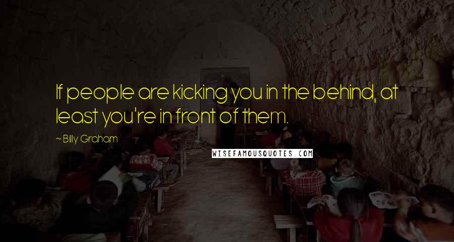 Billy Graham Quotes: If people are kicking you in the behind, at least you're in front of them.