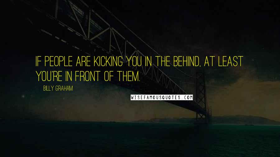 Billy Graham Quotes: If people are kicking you in the behind, at least you're in front of them.