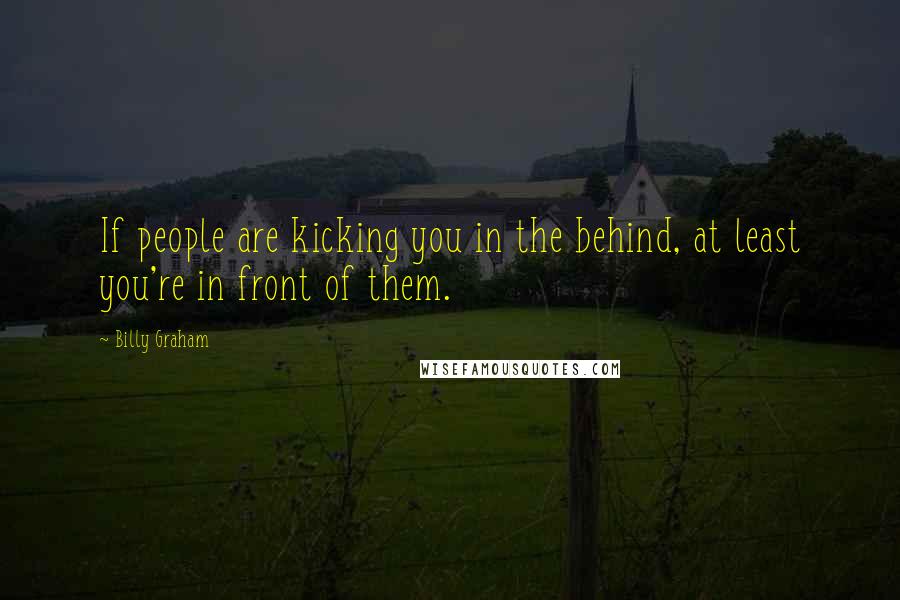 Billy Graham Quotes: If people are kicking you in the behind, at least you're in front of them.