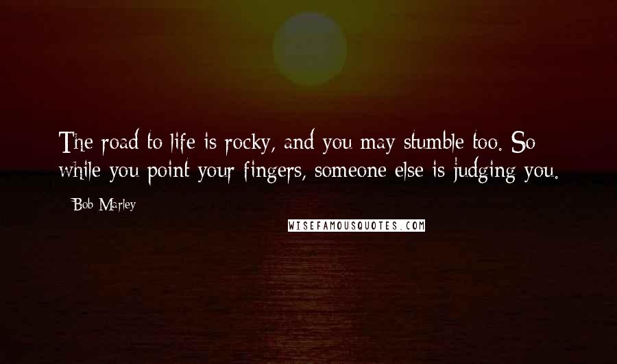 Bob Marley Quotes: The road to life is rocky, and you may stumble too. So while you point your fingers, someone else is judging you.