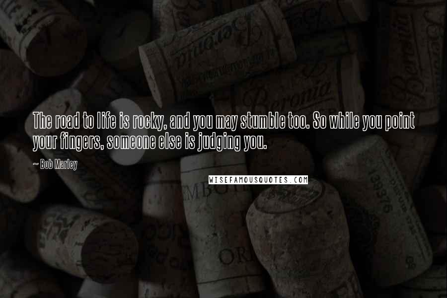 Bob Marley Quotes: The road to life is rocky, and you may stumble too. So while you point your fingers, someone else is judging you.