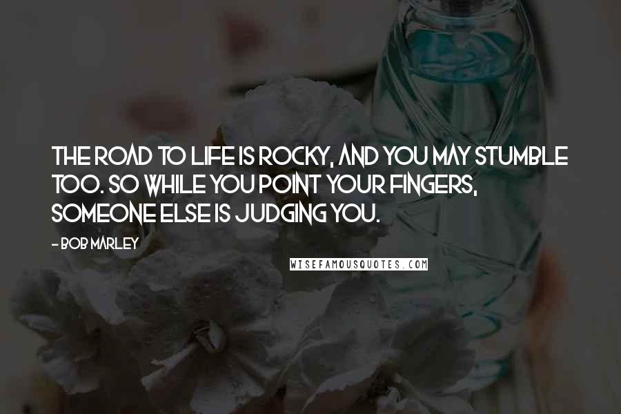 Bob Marley Quotes: The road to life is rocky, and you may stumble too. So while you point your fingers, someone else is judging you.