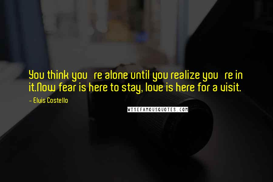 Elvis Costello Quotes: You think you're alone until you realize you're in it.Now fear is here to stay, love is here for a visit.