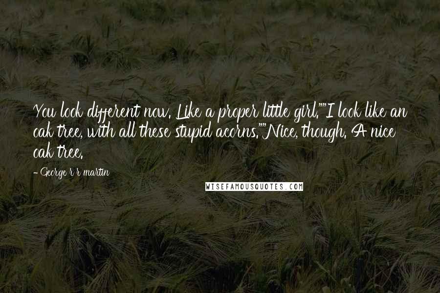 George R R Martin Quotes: You look different now. Like a proper little girl.""I look like an oak tree, with all these stupid acorns.""Nice, though. A nice oak tree.