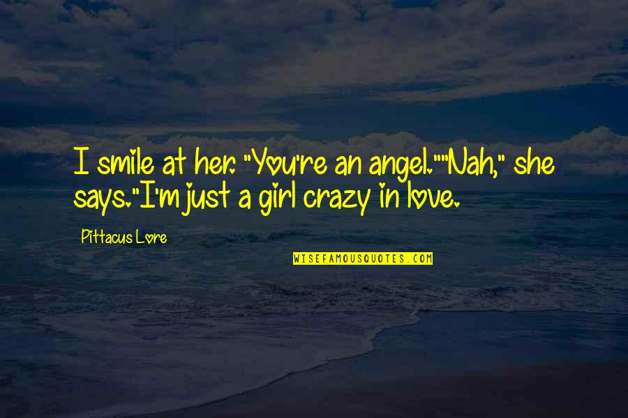A Girl With Smile Quotes By Pittacus Lore: I smile at her. "You're an angel.""Nah," she