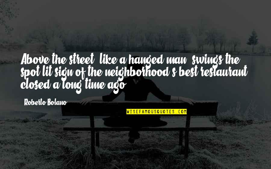 Best Restaurant Quotes By Roberto Bolano: Above the street, like a hanged man, swings