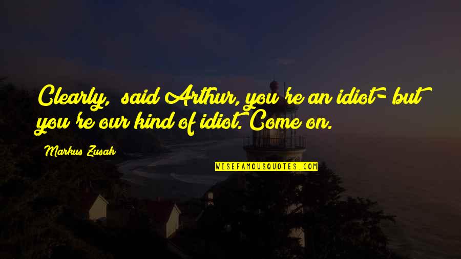 Book Thief Book Quotes By Markus Zusak: Clearly," said Arthur,"you're an idiot- but you're our Book Thief Book Quotes By Markus Zusak: Clearly," said Arthur,"you're an idiot- but you're our