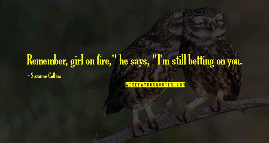 Girl On Fire Quotes By Suzanne Collins: Remember, girl on fire," he says, "I'm still