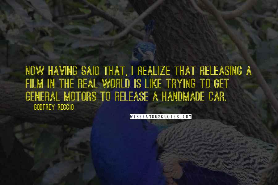 Godfrey Reggio quotes: Now having said that, I realize that releasing a film in the real world is like trying to get General Motors to release a handmade car.