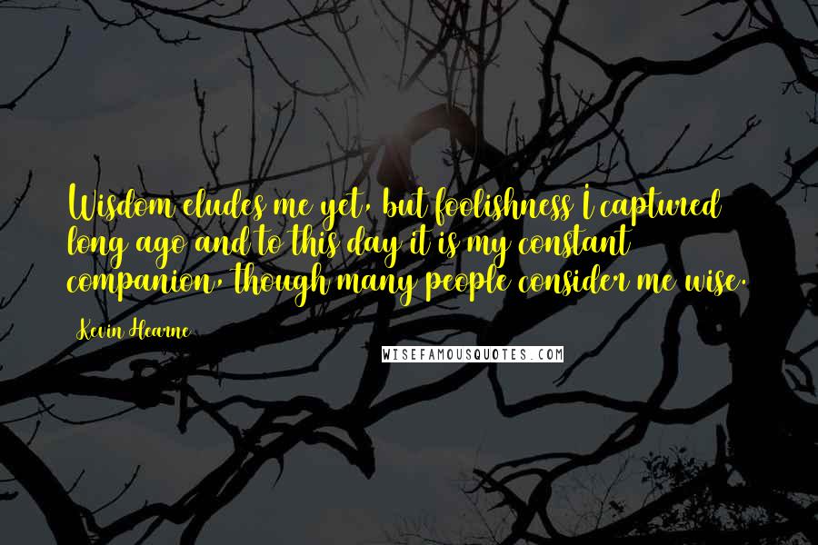 Kevin Hearne quotes: Wisdom eludes me yet, but foolishness I captured long ago and to this day it is my constant companion, though many people consider me wise.