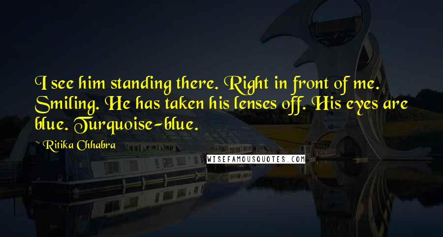 Ritika Chhabra quotes: I see him standing there. Right in front of me. Smiling. He has taken his lenses off. His eyes are blue. Turquoise-blue.