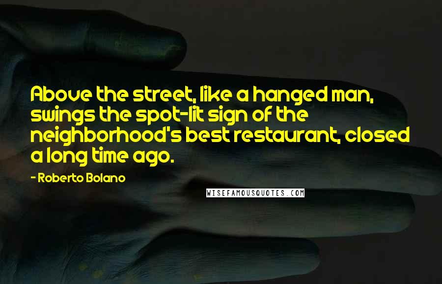 Roberto Bolano quotes: Above the street, like a hanged man, swings the spot-lit sign of the neighborhood's best restaurant, closed a long time ago.