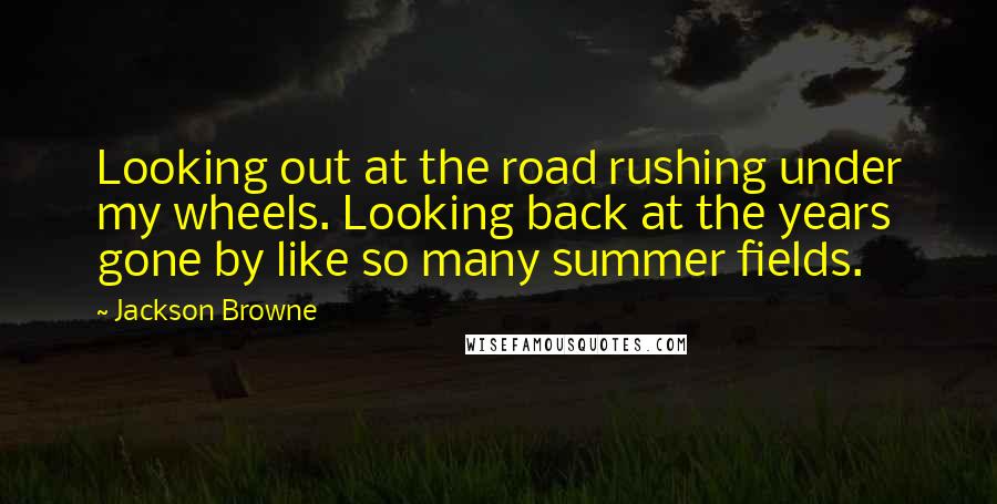 Jackson Browne Quotes: Looking out at the road rushing under my wheels. Looking back at the years gone by like so many summer fields.