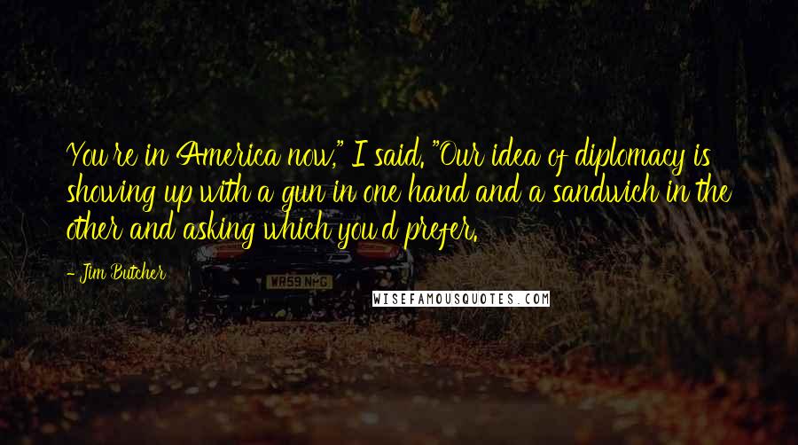 Jim Butcher Quotes: You're in America now," I said. "Our idea of diplomacy is showing up with a gun in one hand and a sandwich in the other and asking which you'd prefer.