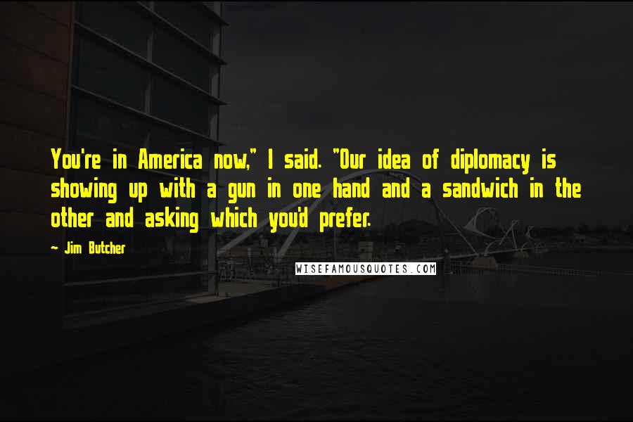 Jim Butcher Quotes: You're in America now," I said. "Our idea of diplomacy is showing up with a gun in one hand and a sandwich in the other and asking which you'd prefer.