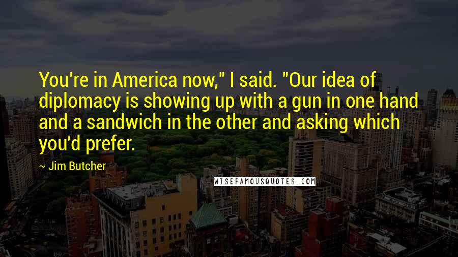 Jim Butcher Quotes: You're in America now," I said. "Our idea of diplomacy is showing up with a gun in one hand and a sandwich in the other and asking which you'd prefer.