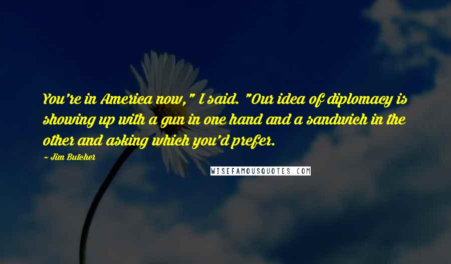 Jim Butcher Quotes: You're in America now," I said. "Our idea of diplomacy is showing up with a gun in one hand and a sandwich in the other and asking which you'd prefer.