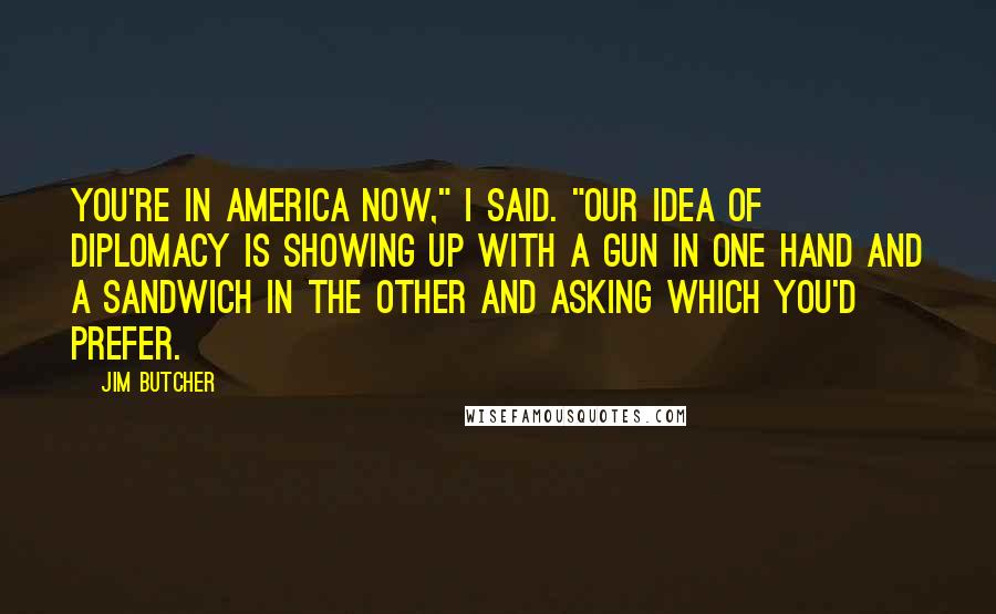 Jim Butcher Quotes: You're in America now," I said. "Our idea of diplomacy is showing up with a gun in one hand and a sandwich in the other and asking which you'd prefer.