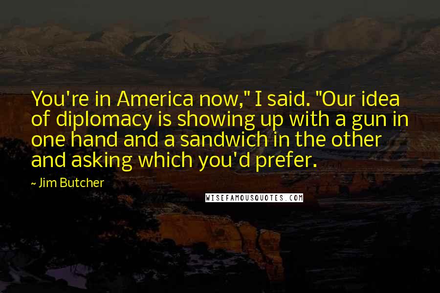 Jim Butcher Quotes: You're in America now," I said. "Our idea of diplomacy is showing up with a gun in one hand and a sandwich in the other and asking which you'd prefer.