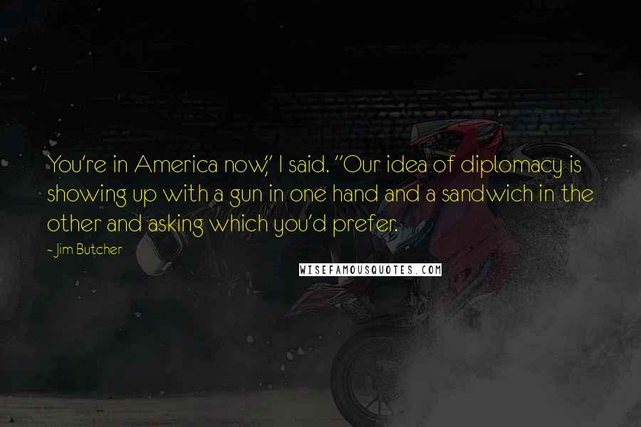 Jim Butcher Quotes: You're in America now," I said. "Our idea of diplomacy is showing up with a gun in one hand and a sandwich in the other and asking which you'd prefer.