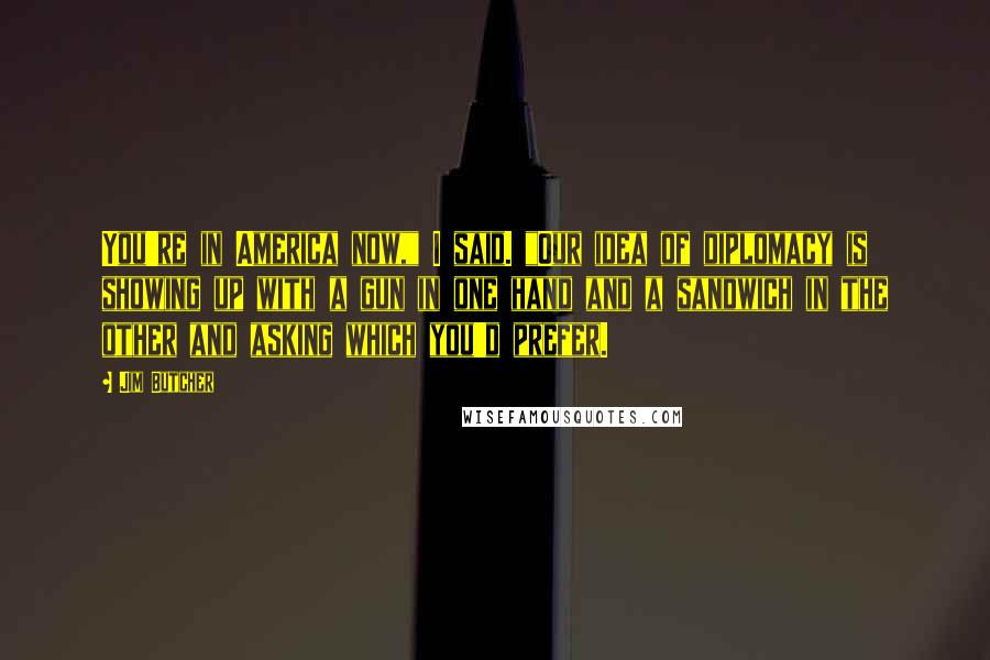 Jim Butcher Quotes: You're in America now," I said. "Our idea of diplomacy is showing up with a gun in one hand and a sandwich in the other and asking which you'd prefer.