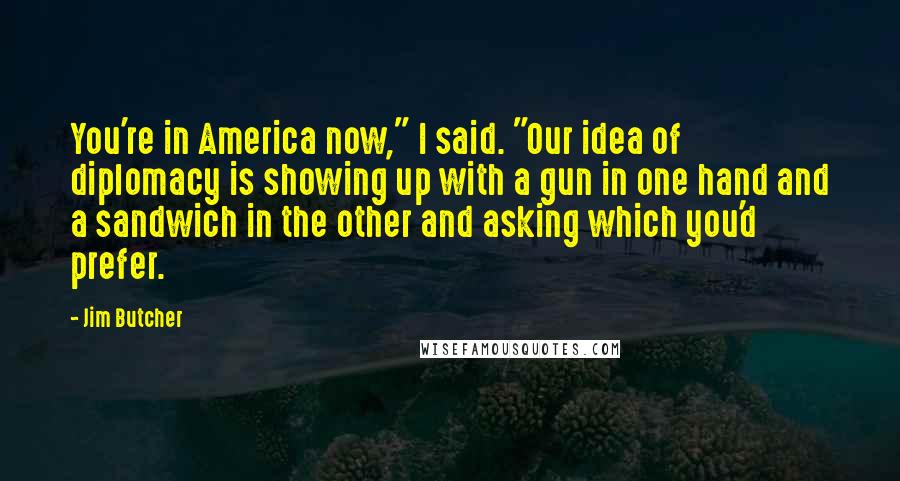 Jim Butcher Quotes: You're in America now," I said. "Our idea of diplomacy is showing up with a gun in one hand and a sandwich in the other and asking which you'd prefer.