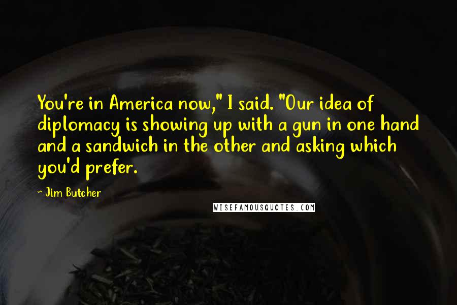 Jim Butcher Quotes: You're in America now," I said. "Our idea of diplomacy is showing up with a gun in one hand and a sandwich in the other and asking which you'd prefer.