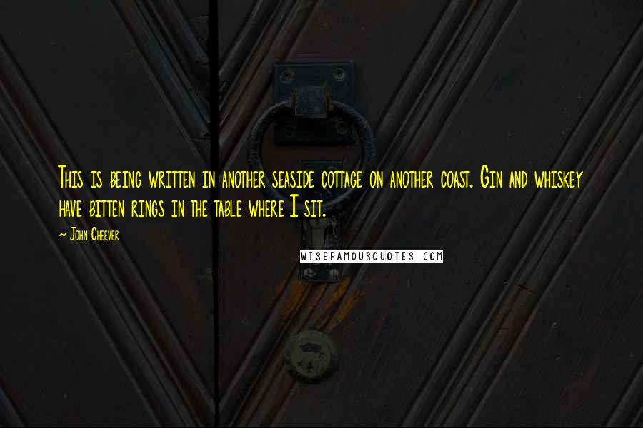 John Cheever Quotes: This is being written in another seaside cottage on another coast. Gin and whiskey have bitten rings in the table where I sit.