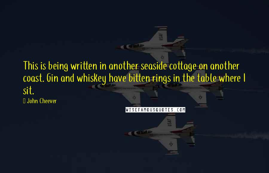 John Cheever Quotes: This is being written in another seaside cottage on another coast. Gin and whiskey have bitten rings in the table where I sit.