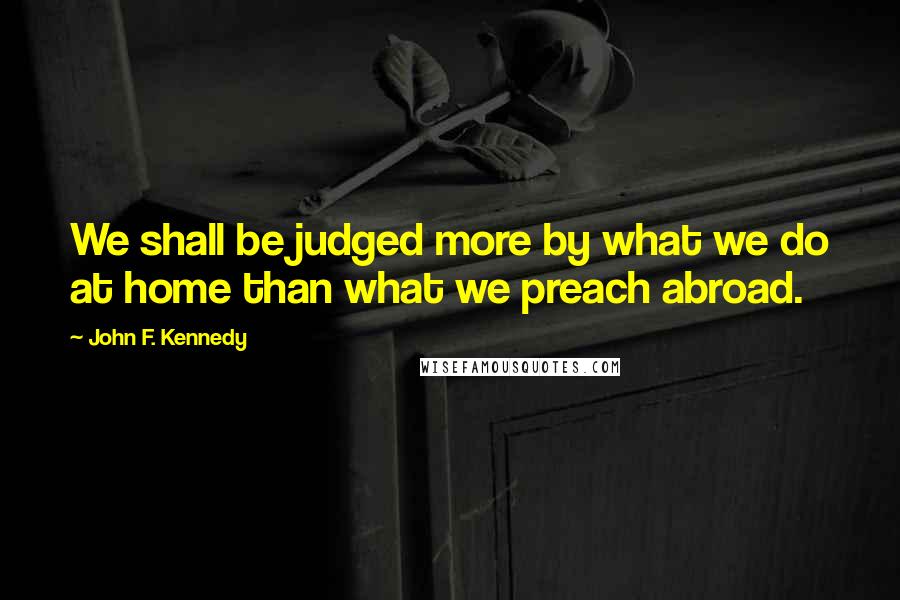 John F. Kennedy Quotes: We shall be judged more by what we do at home than what we preach abroad.