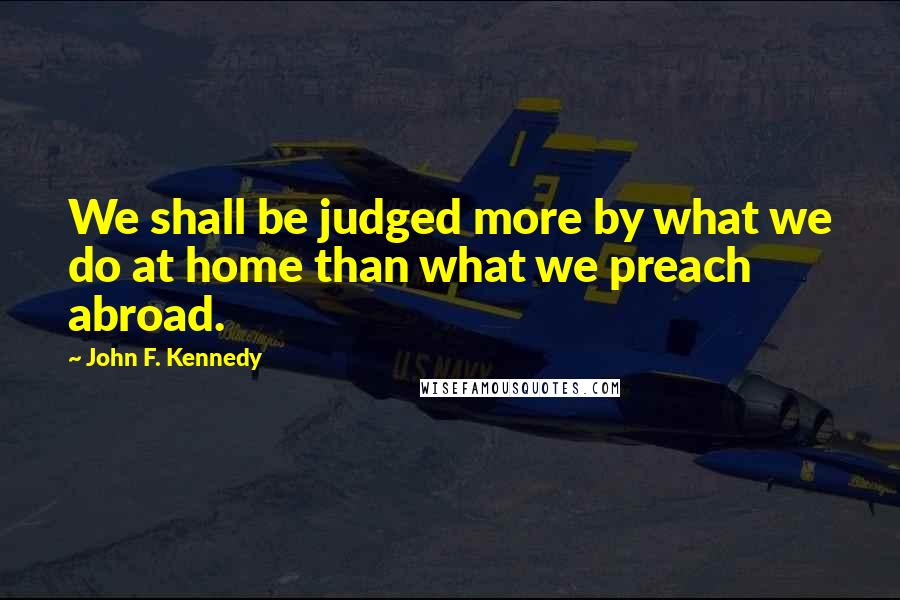 John F. Kennedy Quotes: We shall be judged more by what we do at home than what we preach abroad.