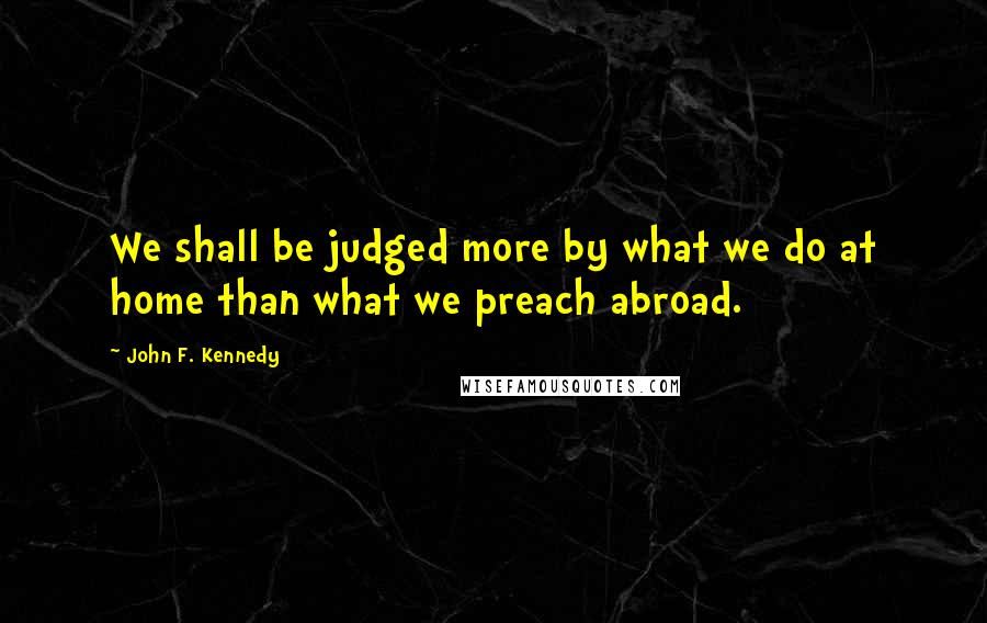 John F. Kennedy Quotes: We shall be judged more by what we do at home than what we preach abroad.