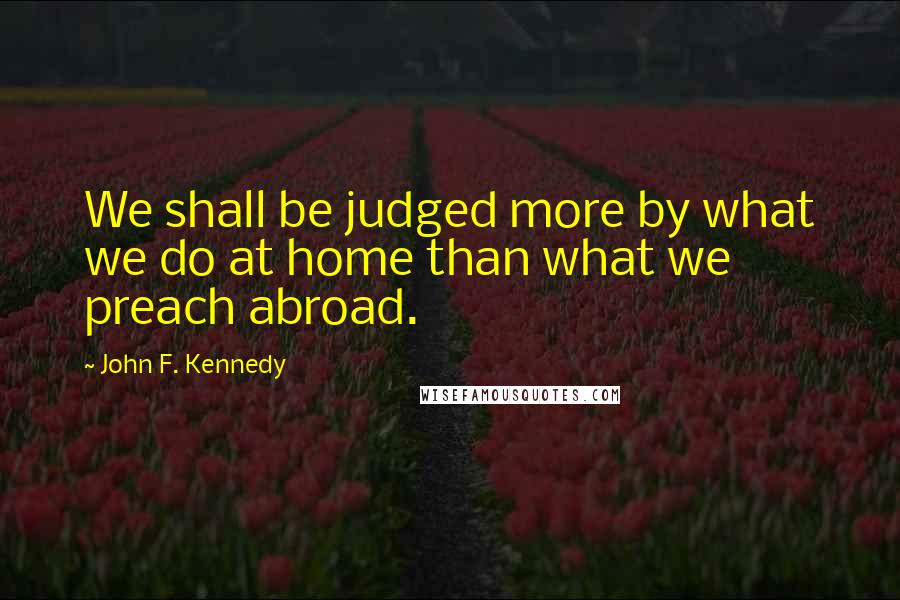John F. Kennedy Quotes: We shall be judged more by what we do at home than what we preach abroad.