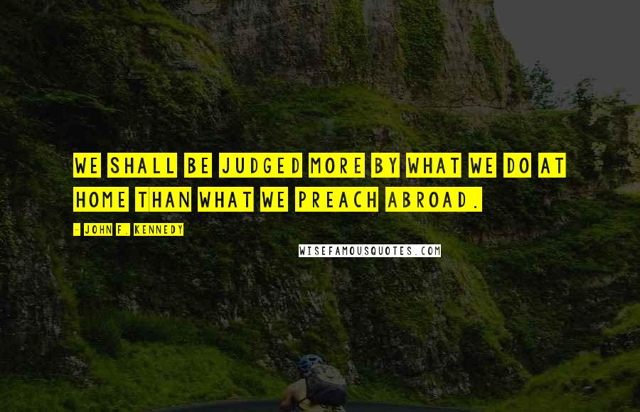 John F. Kennedy Quotes: We shall be judged more by what we do at home than what we preach abroad.