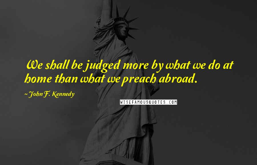 John F. Kennedy Quotes: We shall be judged more by what we do at home than what we preach abroad.