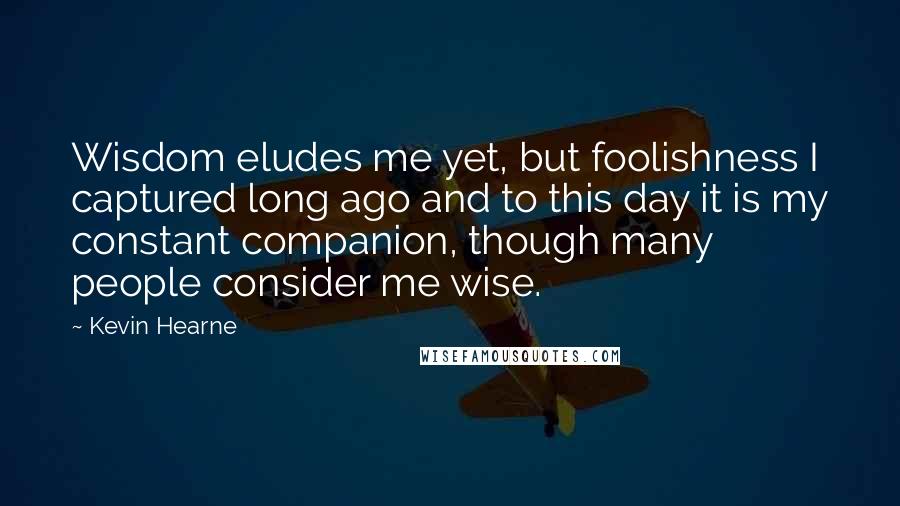 Kevin Hearne Quotes: Wisdom eludes me yet, but foolishness I captured long ago and to this day it is my constant companion, though many people consider me wise.