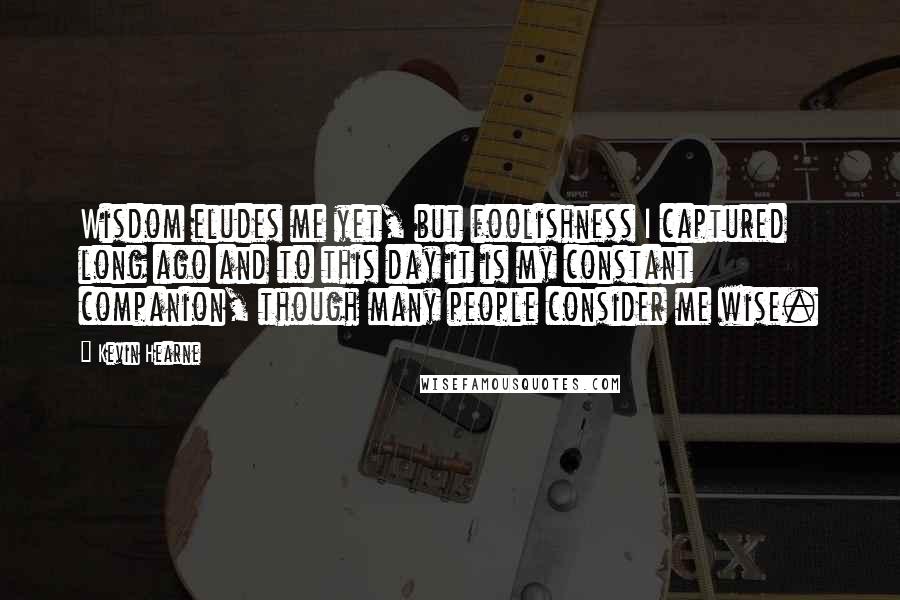 Kevin Hearne Quotes: Wisdom eludes me yet, but foolishness I captured long ago and to this day it is my constant companion, though many people consider me wise.