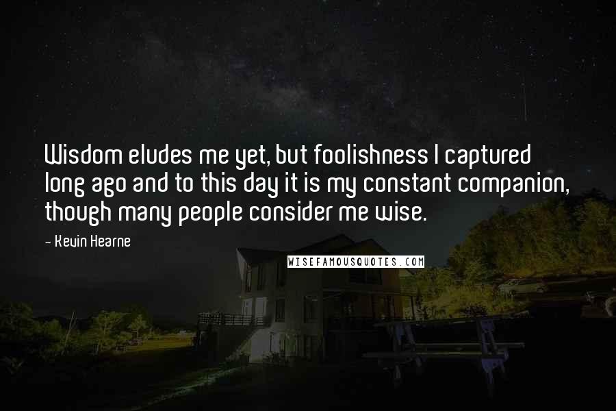 Kevin Hearne Quotes: Wisdom eludes me yet, but foolishness I captured long ago and to this day it is my constant companion, though many people consider me wise.