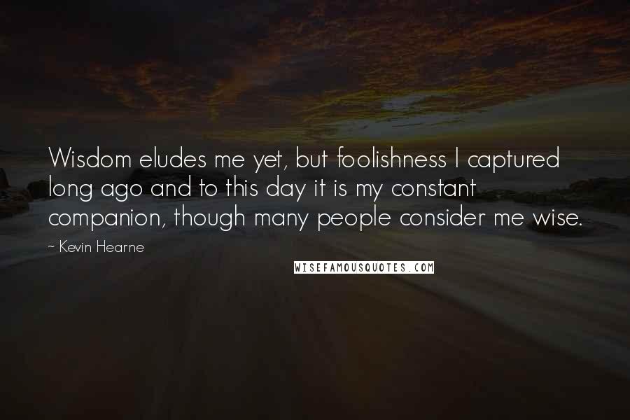 Kevin Hearne Quotes: Wisdom eludes me yet, but foolishness I captured long ago and to this day it is my constant companion, though many people consider me wise.